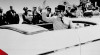 Foto Presiden Sukarno (berpeci) melambaikan tangan kepada kerumunan masyarakat dan wartawan ketika melintasi Sungai Potomac dalam kunjungannya ke Amerika Serikat pada 30 Mei 1956.